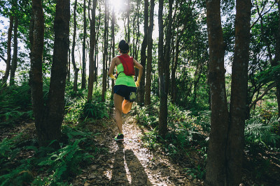 年轻女子trail runner在日出热带森林跑步
