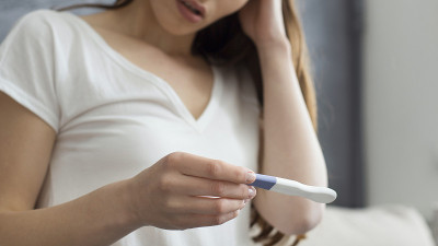 失望的妇女抱着验孕棒的裁剪图像