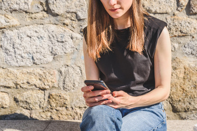 一个年轻漂亮的红发女人坐在长椅上拿着智能手机