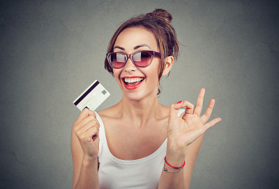 快乐的年轻女人戴着太阳镜和信用卡给ok的标志