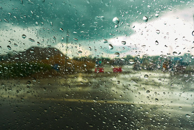 模糊的背景与雨滴在汽车玻璃上。在雨中骑行