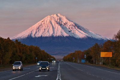 汽车沿着道路上的背景火山在日落太阳