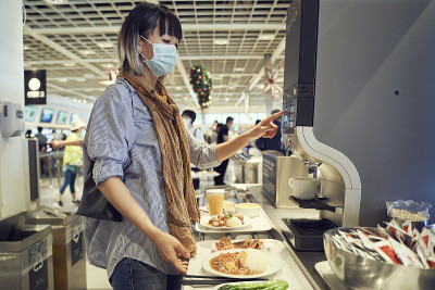 亚洲妇女戴着面具在大流行期间在自助餐厅为自己煮咖啡