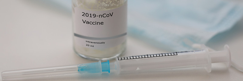 装新型冠状病毒疫苗的瓶子放在桌上，空注射器