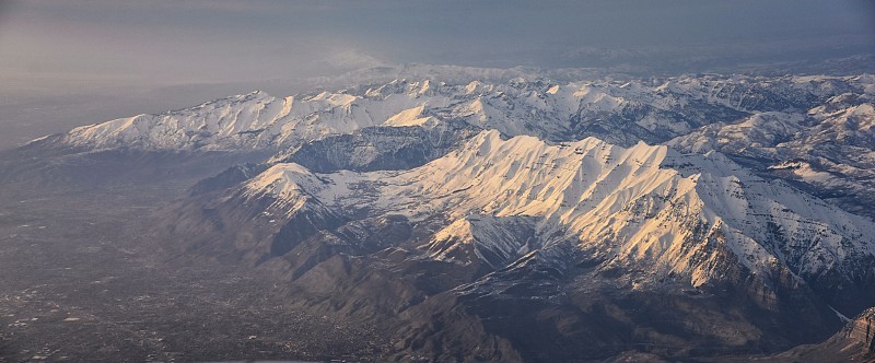 从飞机上鸟瞰瓦萨奇前落基山脉的雪峰在冬天包括城市普罗沃，法明顿Bountiful, Orem和盐湖城