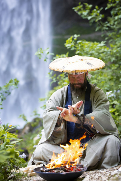 奥地利大瀑布前，一名蓄着胡须、穿着日式长袍的欧洲男子正在举行火葬仪式