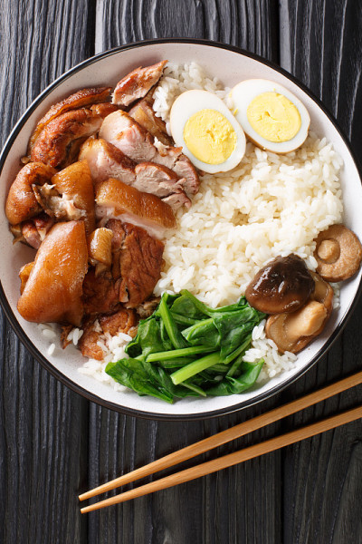 炖猪腿配米饭，鸡蛋和香草泰式Khao Kha Moo在碗里的特写。垂直的俯视图