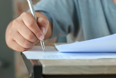 教育测试在学校考试的概念:大学生拿着纸笔记录文档表参加考试的讲座把椅子在教室里考试。评价学习中的课堂