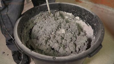 建筑工人混合找平剂，抹灰地板，准备铺拼花地板。工人在桶里搅拌填料地板