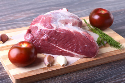 生猪肉排放在木板上，配上香草、大蒜、香料和西红柿。有选择性的重点。