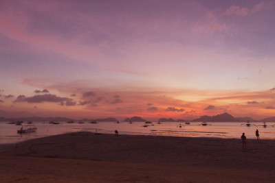 热带海滩上美丽的日落。鸟瞰图的戏剧性的夜空和船的剪影。风景如画的巴拉望岛，菲律宾。傍晚热带海景。夏季