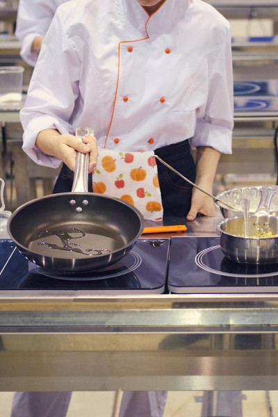 厨师在咖啡馆的大厨房里准备食物，用煎锅烤