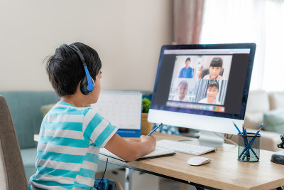 亚洲男生视频会议电子学习与老师和同学在电脑上在家里的客厅。在家教育和远程学习，在线，教育和互联网。