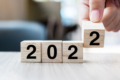 商人手持木质立方体与翻转块2021年至2022年的文本在桌子的背景。决议，策略，解决方案，目标，业务