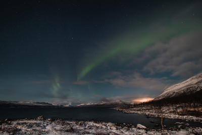 在芬兰拉普兰的Kilpisjarvi，在一个无云的夜晚，北极光扫过一个大湖。绿莹莹的北极光在天空中舞