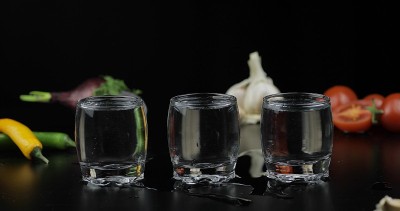 用小酒杯喝伏特加。背景用蔬菜