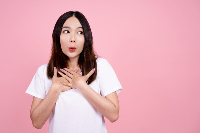 亚洲女孩很惊讶，她很兴奋。粉色背景工作室。