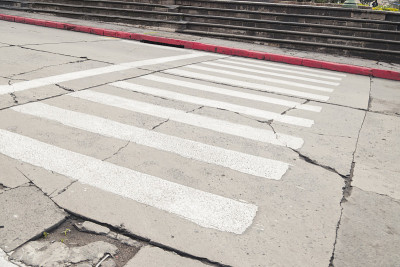 旧的破旧道路上的白色斑马线——城市中被忽视的旧街道上的斑马线。