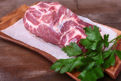 生猪颈剁肉和欧芹叶在石头背景上。准备做饭。
