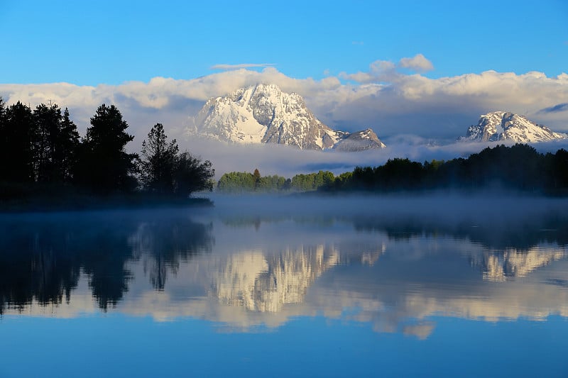 美丽的雪山景观与雾和反射