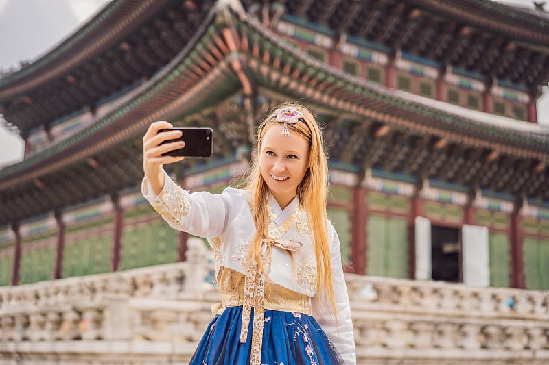 身穿韩服的年轻白种女游客在韩国宫殿。韩国旅游概念。国家韩国的服装。为游客提供的娱乐——试穿韩国民族服