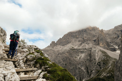 Oberbachernspitze -女人背着大背包和棍子，走在意大利高白云石的木楼梯上。-一个女人