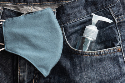 Anti-coronavirus喷雾。一个男人把它放在裤子口袋里
