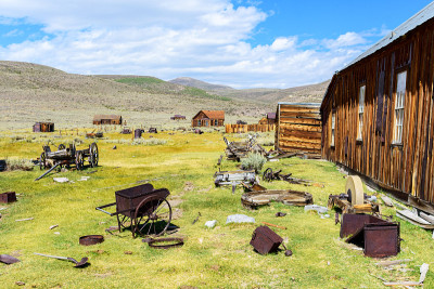 在Bodie State Historic Park废弃的木制建筑附近，陈旧生锈的设备在盛开的景观上