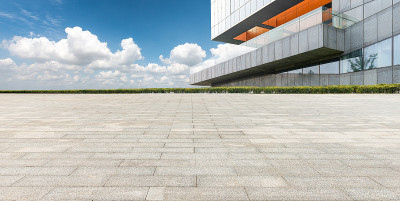 在晴空万里的天空下，城市中心的建筑物后面是石砌的广场