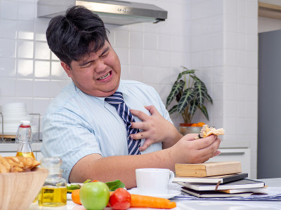 亚洲胖男人吃东西时感到心痛。心脏病发作，胸痛的男人。