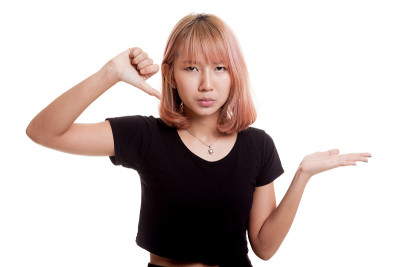 年轻的亚洲妇女显示手掌和拇指向下。