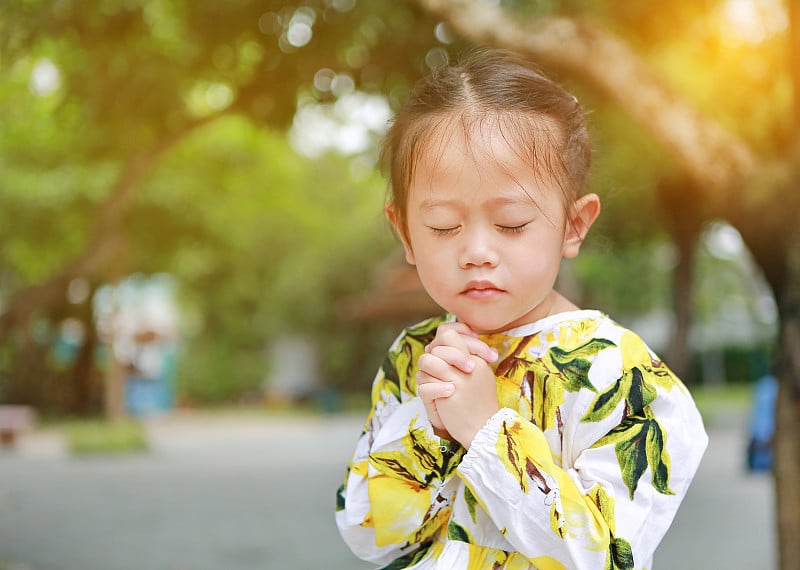 可爱的亚洲小女孩在花园里祈祷。灵性和宗教。