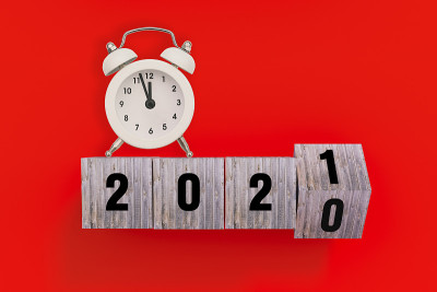 每年的变化。改变日期的圣诞节想法。从2020年过渡到2021年。红色背景上的木制立方体和闹钟。圣诞节