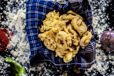 著名的神田巴吉饼或pakora在一个容器里，在黑色的表面上和鹰嘴豆粉，香料，洋葱，和所有其他的原料一
