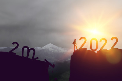 一个活跃的运动员和一个背包客的剪影在顶峰，数字是2021年到2022年的未来。成就、目标和远景概念。