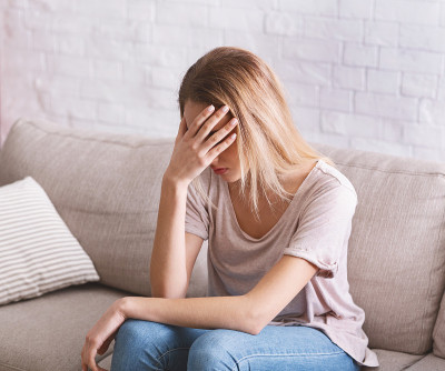女孩用手捂着脸呆在家里隔离