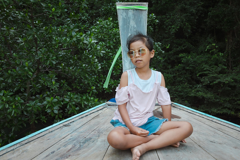 可爱的亚洲女孩坐在长尾木船的头在海上旅行去惊人的岛屿和泻湖