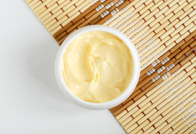 黄色发膜(香蕉面霜，乳木果面膜，身体黄油)在小的白色罐子里。自然的皮肤和头发概念。俯视图，复制空间。