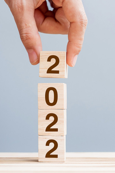 手持木质立方体块与2022文本的桌子背景。决心，计划，回顾，目标，开始和新年假期的概念