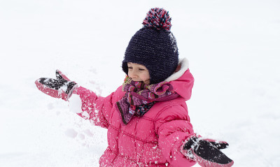 一个穿着暖和的小女孩在玩雪。