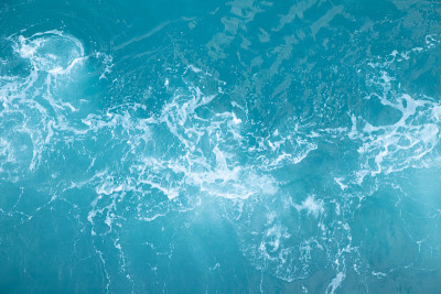 海浪在海浪中溅起波纹水。水蓝色背景。