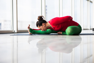 Djanu-shirasana。美丽的瑜伽女人在一个大窗户练习