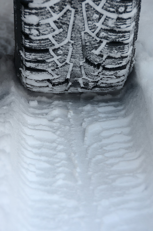 有尖钉的冬季轮胎和雪地上的痕迹，特写