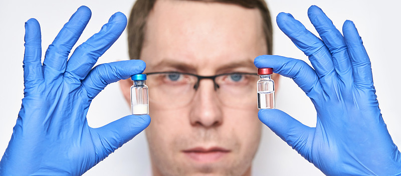Person in gloves hold two vaccine bottles