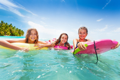 三个女孩骑着冲浪板在海里游泳