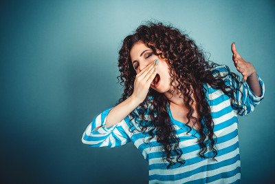 昏昏欲睡的年轻女子张大了嘴打哈欠，眼睛闭着看
