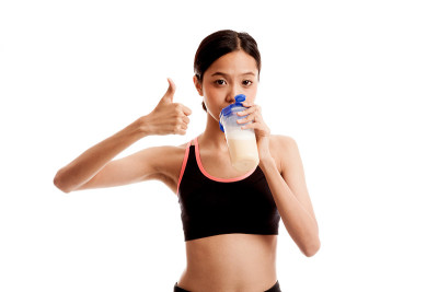 美丽的亚洲健康女孩显示拇指喝乳清