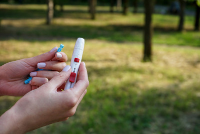 一个年轻女子手中拿着一支柳叶刀笔在街上，上面有文字的空间。糖尿病的概念。