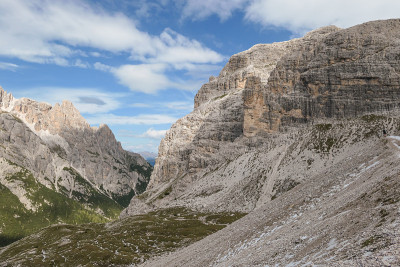 在Dolomites山谷的全景，意大利。周围有陡峭的山坡。很多石头和鹅卵石都丢失了。天空中布满了柔和
