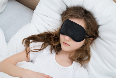 戴着睡眠面罩睡在床上的女孩